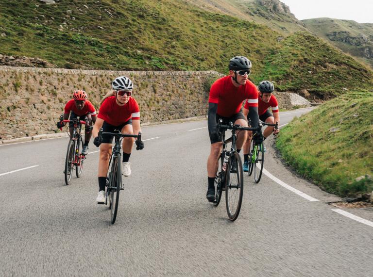 Four cyclists on road bikes tackling a mountainside road.