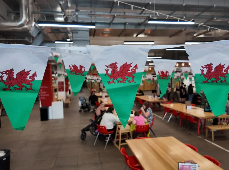 canteen area with Welsh flag bunting with people, tables and chairs.