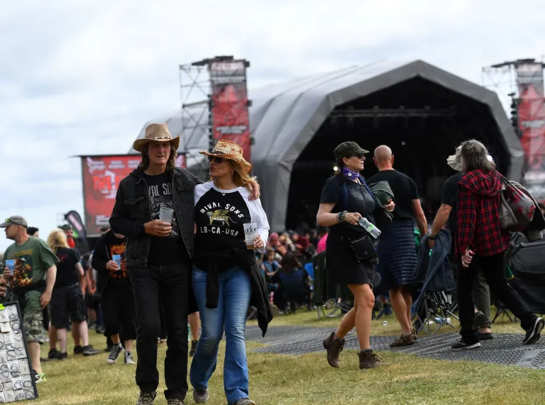 people walking at festival with stage in background.