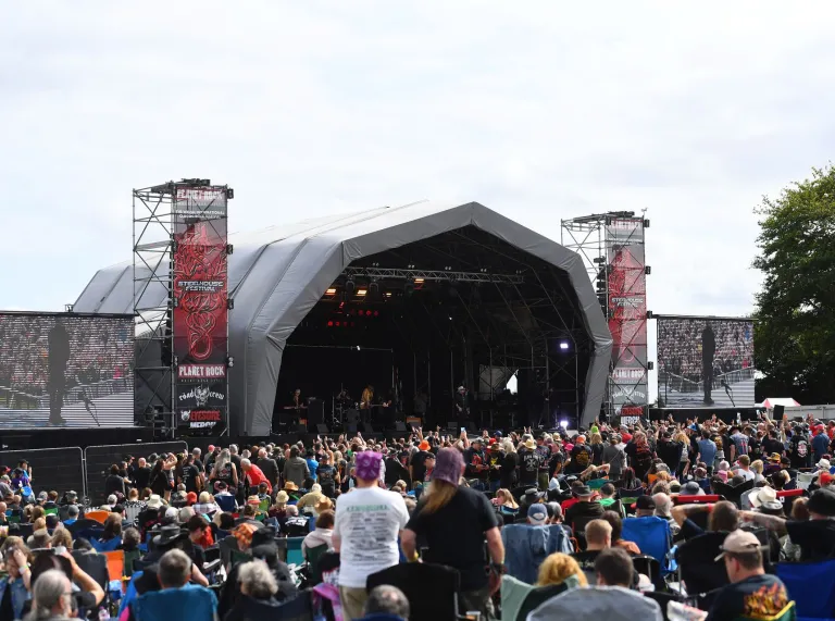 a crowd of people facing a festival stage.
