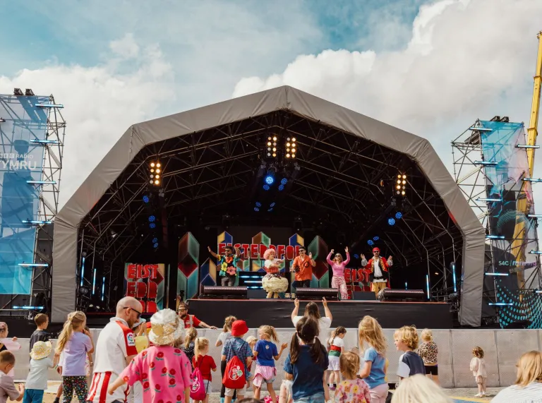 people, mostly children enjoying show on stage at Eisteddfod.