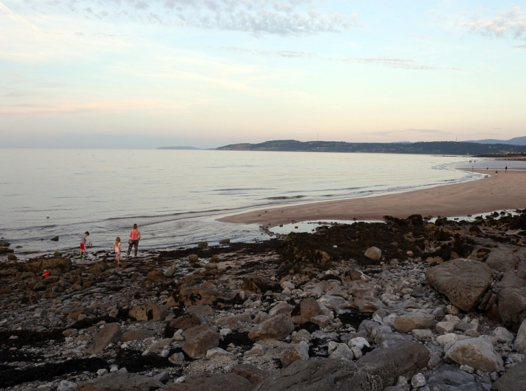 A family exploring a rocky and sandy beach.