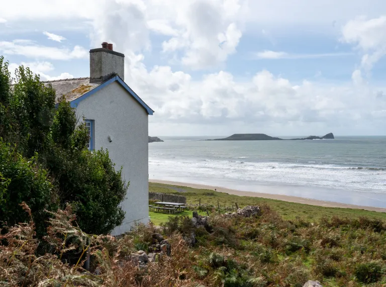 Side of a white painted house looking out to the sea 