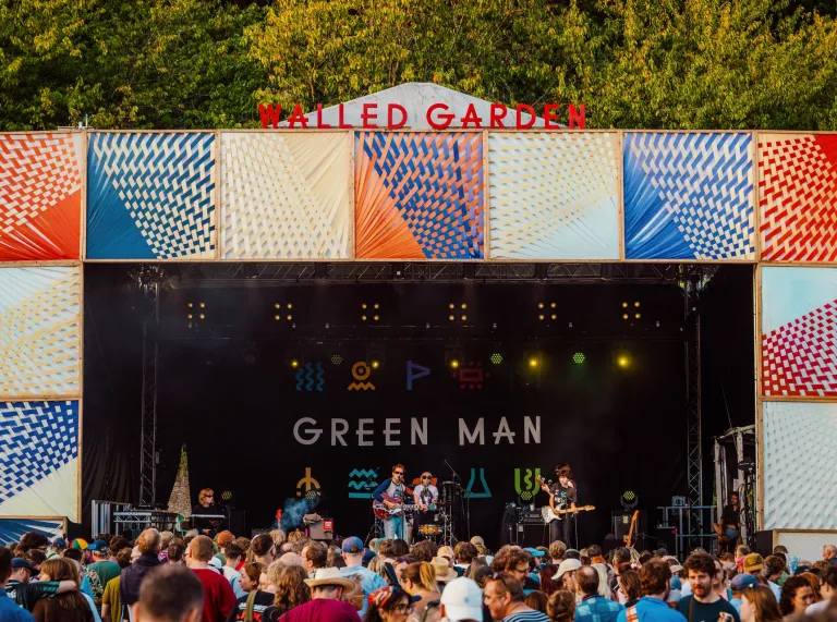 band playing at festival on a sunny day with crowd watching.