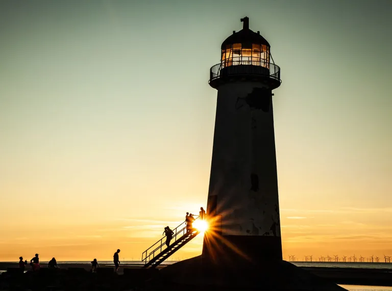 A lighthouse silhouetted against a sunset.