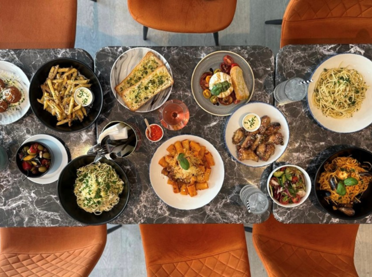 a table set with a variety of pasta dishes, sides, and drinks viewed from above.