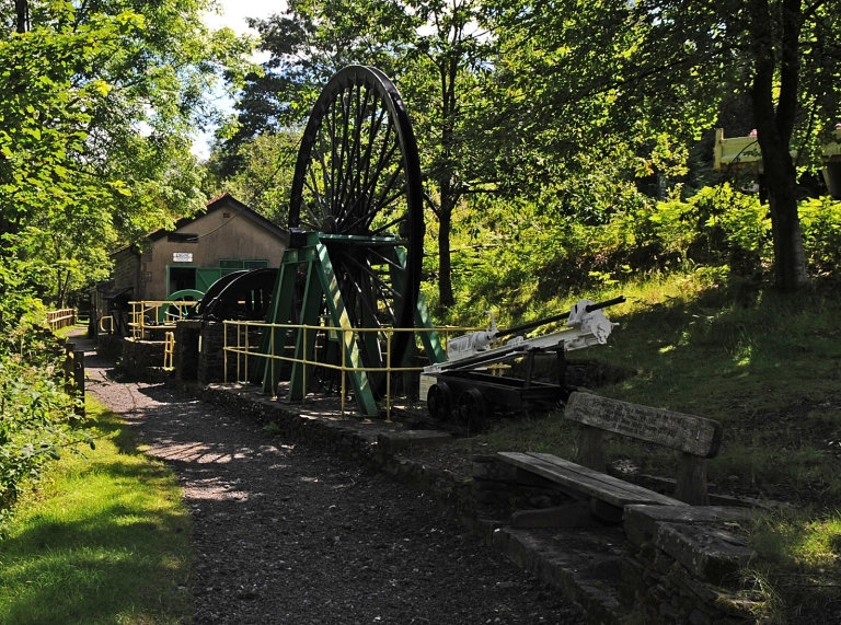 Exterior shot of museum with wheel and path and bench in foreground.