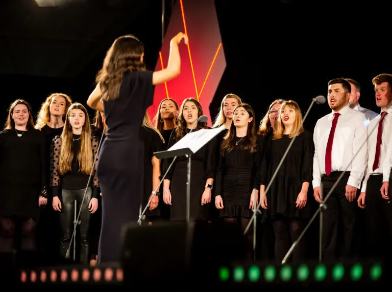 Choir singing on stage in black tshirts