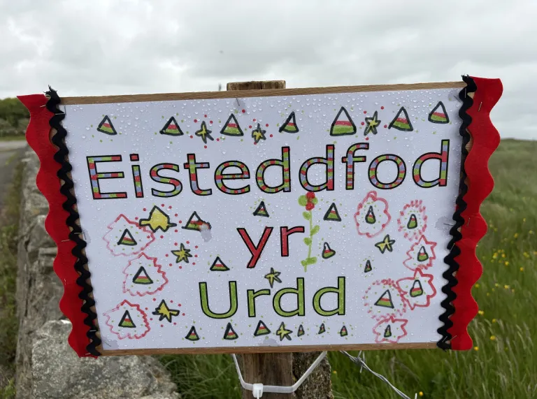 Colourful sign of the Urdd colours on a wooden sign