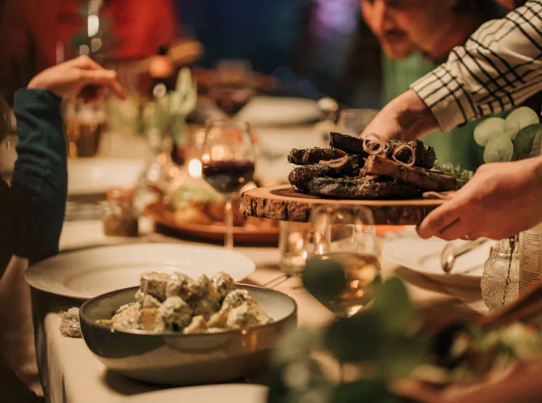 A table laid with food, wine and serving dishes ready for a meal.