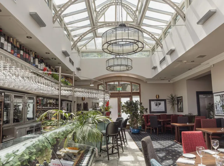 Bright dining area at The Custom House with a glass roof, bar and restaurant seating.