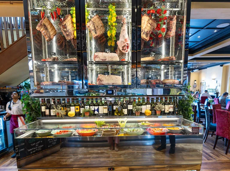 Dry-ageing cabinet displaying hanging cuts of meat inside The Custom House restaurant