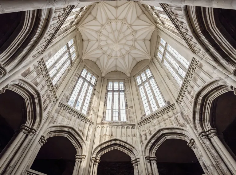 Intricate Gothic-style vaulted ceiling and tall arched windows inside the entrance hall at Margam Castle.