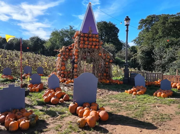 Halloween graveyard display with pumpkins and a pumpkin-covered arch.