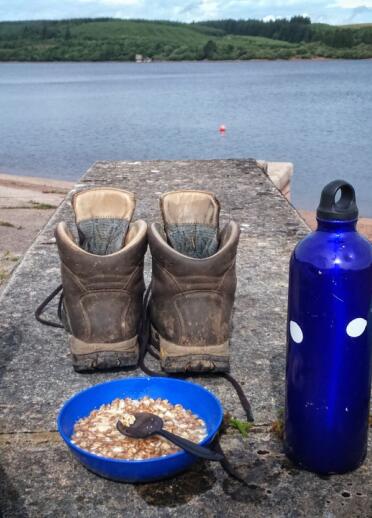 View of walker's feet in socks with boots and breakfast next to them