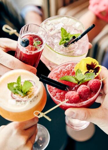 A variety of colourful refreshing drinks adorned with fruit and mint.