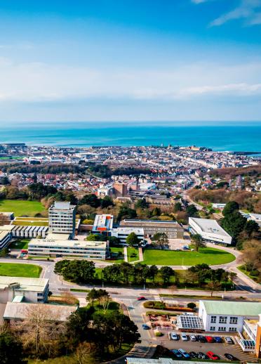 An aerial shot of a university campus with the sea beyond.