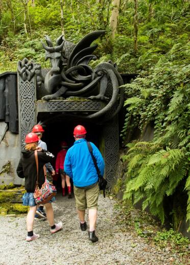 A group entering King Arthur's Labyrinth with an imposing dragon above the entrance.