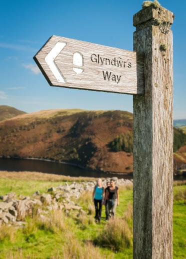 Three female walkers on Glyndwr's Way path above Llyn Clywedog.