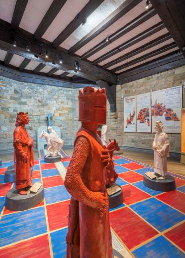 Lifesize knights, kings and queens set on a chequered floor in a castle.