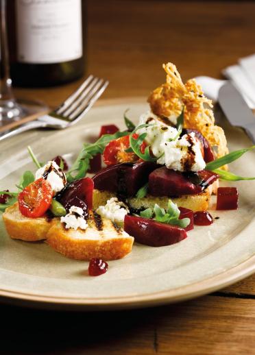 A dish of tomatoes, lettuce, beetroot cheese and crostini.