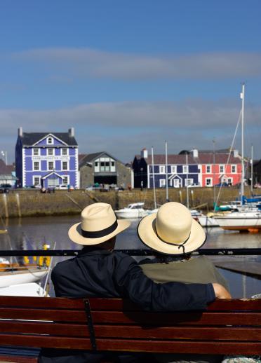 Ein Paar blickt auf den Hafen von Aberaeron und das Harbourmaster Hotel im Hintergrund.