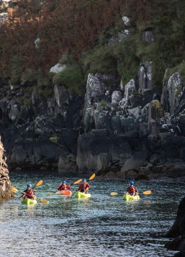 People in kayaks in a sea cove.