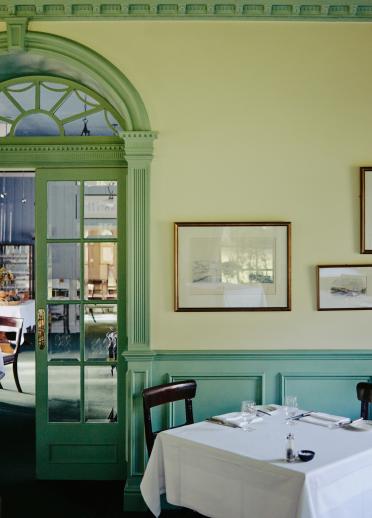 The interior of the restaurant at Tyddyn Llan, Llandrillo - featuring a table with antique chairs.