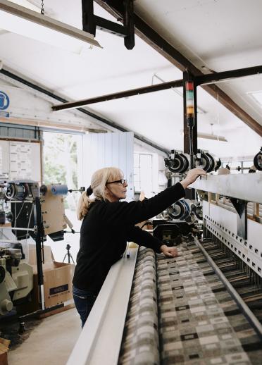 Woman operating woollen mill machinery