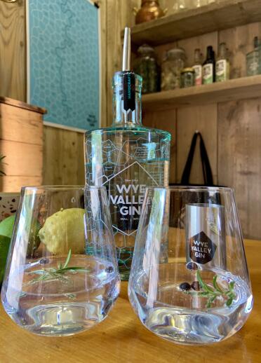 Eine Flasche Wye Valley Gin aus der Silver Circle Distillery und zwei Gläser mit Gin, Rosmarin und Blaubeeren darin.