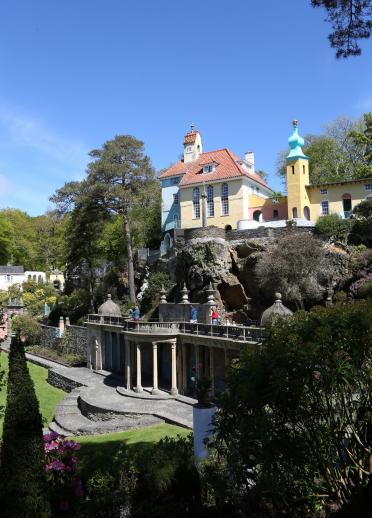 The colourful buildings of the Italianate village of Portmeirion, surrounded by trees.