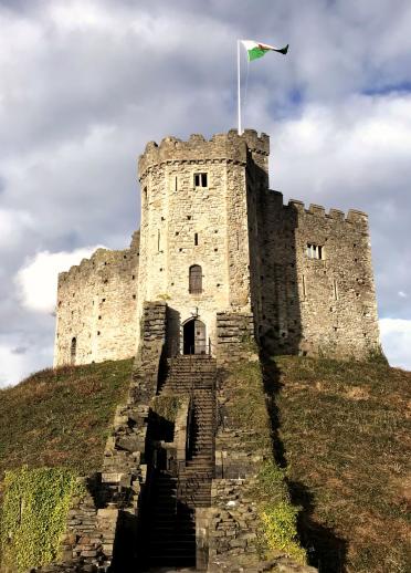 Steps leading up a hill to the Norman Keep with a welsh flag flying at Cardiff Castle.