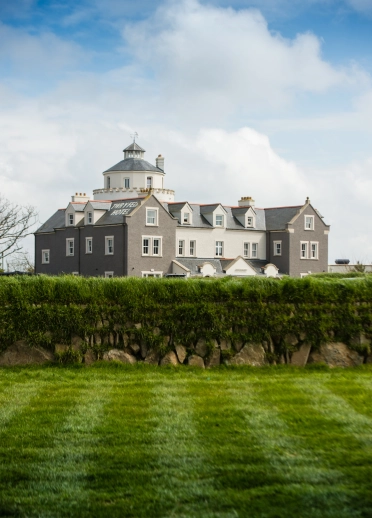 exterior of hotel viewed from beyond hedges.