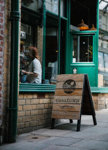 exterior of coffee shop with wooden sign.