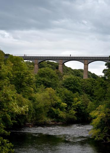 Bild eines Aquädukts und der Bäume sowie des Flusses darunter.