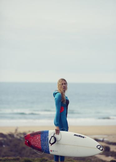 woman on beach holding kite surf board.