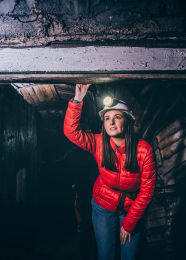 Frau mit Helm und Stirnlampe in einer Mine, Big Pit National Coal Museum.