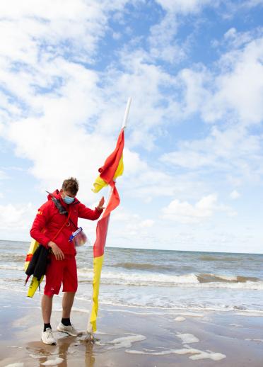 Lifeguard wearing face covering standing on the beach