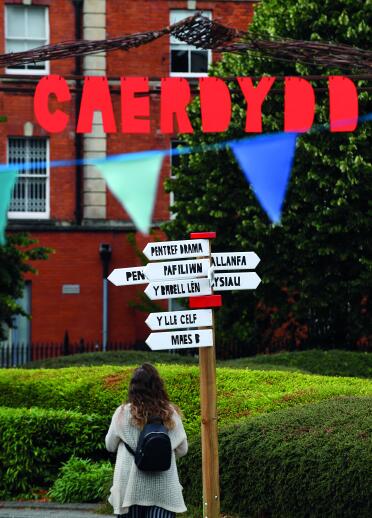 back of woman near sign post with Welsh words, bunting and Caerdydd sign.