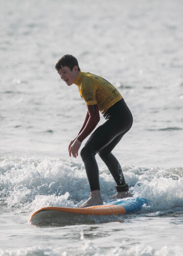 A young man standing up on a surfboard.