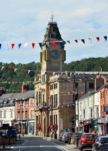 building with a clock tower and shops, plus red, white and blue flags.