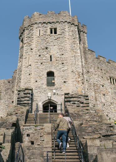A castle keep with two people walking up the steps.