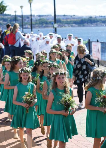 Mädchen in grünen Kleidern mit Blumensträußen.