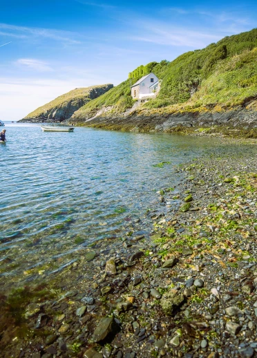 Blick aufs Meer mit einem kleine Steincottage an der grünen Küste