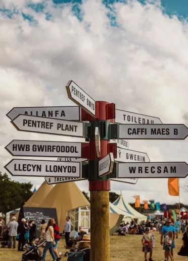 sign in Welsh language at Eisteddfod with people and tents.