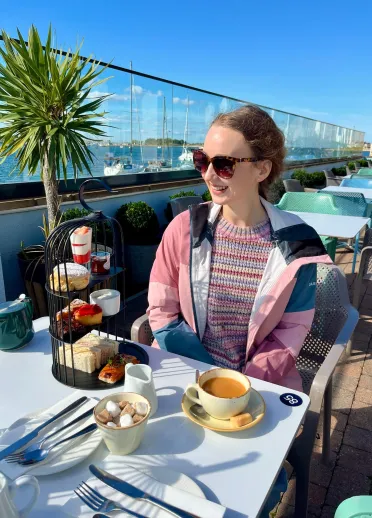 woman with cup of tea sat in outdoor terrace of hotel.