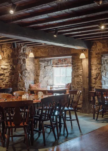 Traditional dining room at the Blue Anchor Inn with exposed stone walls, wooden beams and wooden tables and chairs.