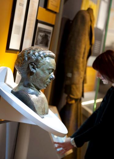 A bust of Dylan Thomas and people exploring exhibits at the Dylan Thomas Centre.