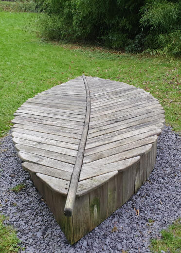 Ein mittelalterlicher Holzstuhl in Form eines Blattes auf einem Wanderweg.