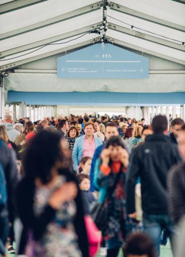 A crown of people walking through a hallway to Hay Festival.